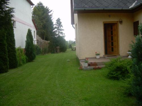 a backyard of a house with a yard with green grass at Éva vendégház in Egerszalók