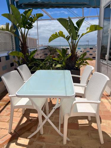 a glass table and chairs on a balcony at Hostal El Alojado de Velarde in Conil de la Frontera