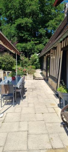 a patio with a table and chairs and trees at Le Vieux Pressoir in Pont-lʼÉvêque