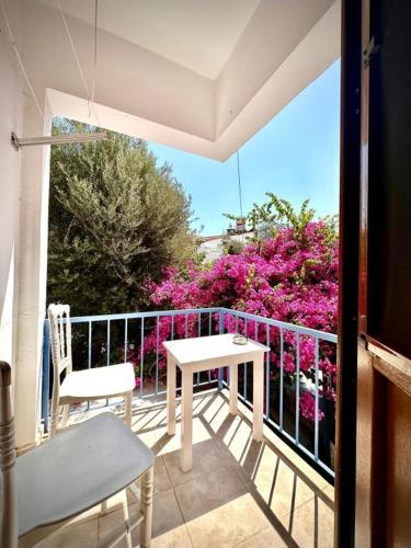 a balcony with a table and chairs and pink flowers at Thetis Pansiyon in Datca