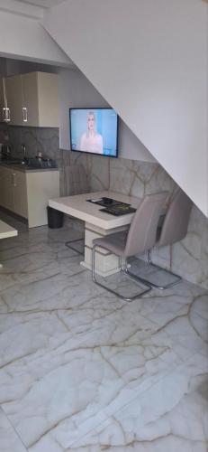 a living room with a table and chairs and a television at Alibaba in Olympiaki Akti