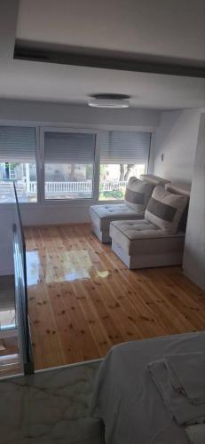 a living room with two couches and a wooden floor at Alibaba in Olympiaki Akti