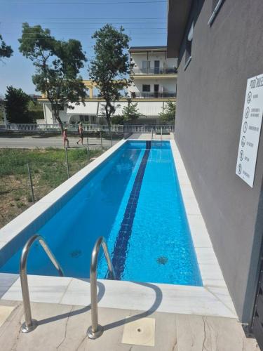 a swimming pool with blue water in front of a building at Alibaba in Olympiaki Akti