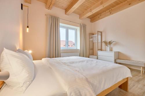 a bedroom with a white bed and a window at Apartmány LehotSKI Guest House in Pavčina Lehota