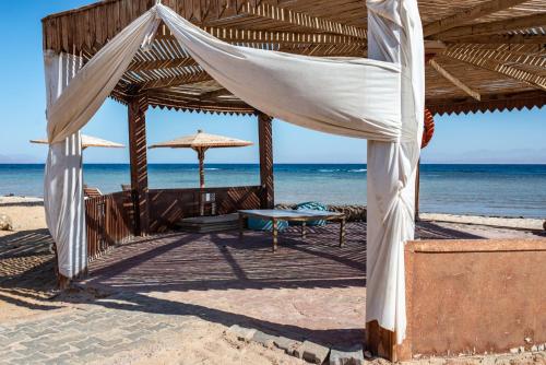 a tent on the beach with a table and an umbrella at Ciao Hotel in Nuweiba