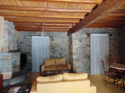 a living room with a couch and a stone wall at Volissos Sea View Maisonettes in Volissos