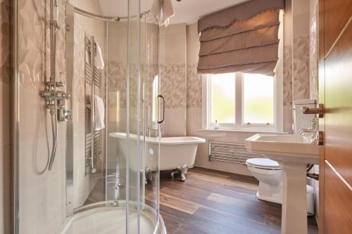 a bathroom with a tub and a toilet and a sink at Kings Park Hotel in Retford