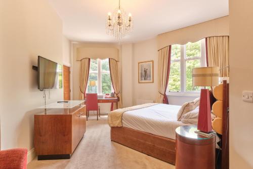 a bedroom with a bed and a desk and windows at Kings Park Hotel in Retford