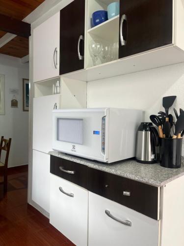 a kitchen with a microwave and a counter top at Casa Cerejeiras in Campos do Jordão