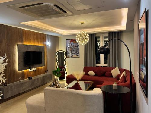 a living room with a red couch and a tv at Luxury Goldcrest Mall Residence Prime Location Serviced Apartments, DHA Lahore in Dargai