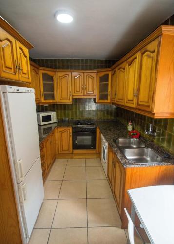 a kitchen with wooden cabinets and a white refrigerator at Casa Saura Y in Benasque