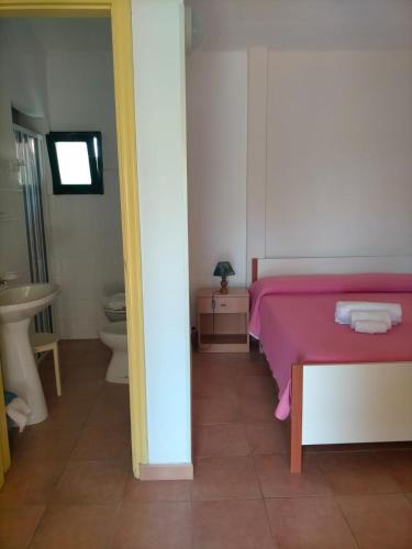 a bedroom with a pink bed and a sink at Villaggio Athragon in Capo Vaticano