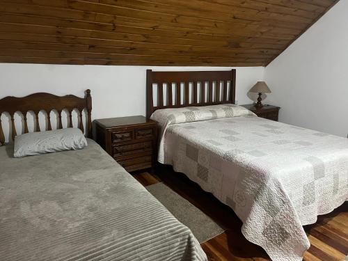 a bedroom with two beds and a wooden ceiling at Casa Cerejeiras in Campos do Jordão