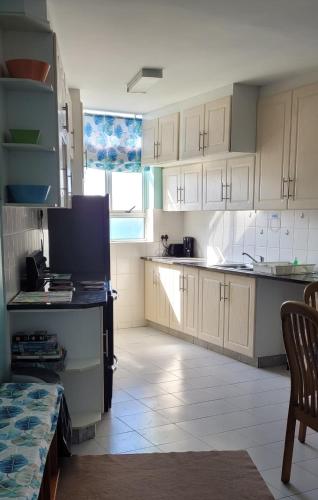a kitchen with white cabinets and a large window at Scottburgh Views - Smile and Wave in Scottburgh