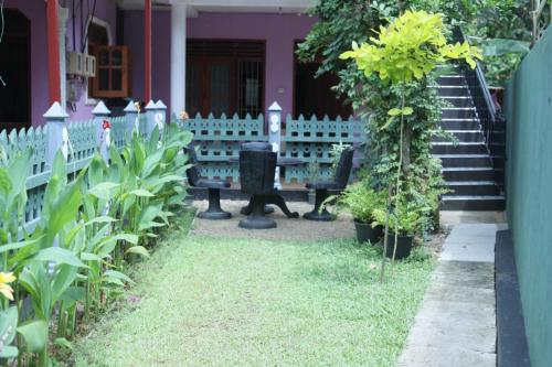 a garden with benches in front of a house at Gin Green Villa in Galle