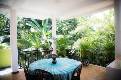 a table and chairs on a porch with trees at Gin Green Villa in Galle
