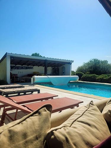 - un canapé installé à côté de la piscine dans l'établissement Chambre Vigne, piscine spa fitness, à Lugon et l’Ile du Carney