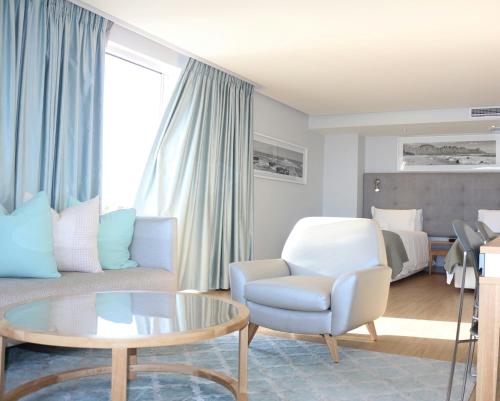 a living room with a couch and a chair and a table at Krystal Beach Hotel in Gordonʼs Bay