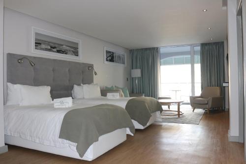a hotel room with a large bed and a chair at Krystal Beach Hotel in Gordonʼs Bay