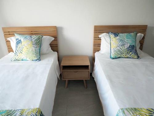 two twin beds in a room with a night stand at Villa Paradisiaque au cœur de Grand Baie in Mauritius