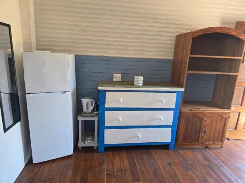 a kitchen with a blue dresser and a white refrigerator at Sunrise Beach Lodge in Ponta Malongane