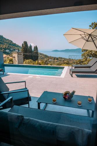 a patio with tables and an umbrella and a pool at Villa Blue Sunset - Stunning Sea View Luxury Villa with Private Heated Pool in Brsečine