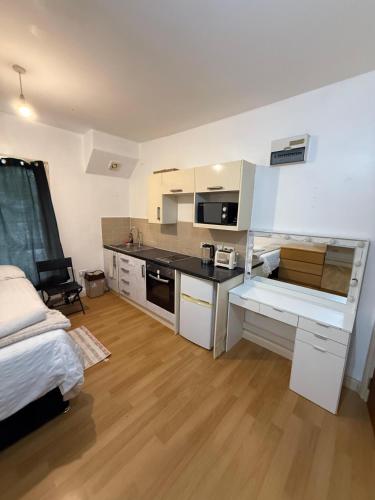 a kitchen with white cabinets and a bed in a room at Beautiful apartment close to central London in London