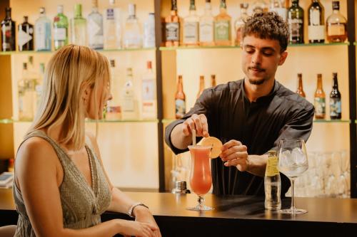 a man and a woman sitting at a bar making a drink at Hotel Món Sant Benet in Sant Fruitos de Bages