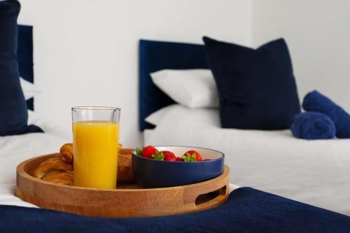 a tray with a glass of orange juice and a bowl of fruit at Modern Studio With Free Parking in Rushden