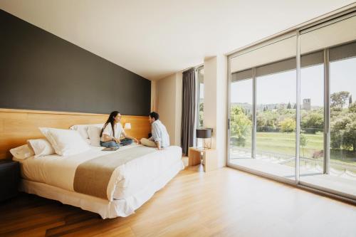 a man and woman sitting on a bed in a bedroom at Hotel Món Sant Benet in Sant Fruitos de Bages