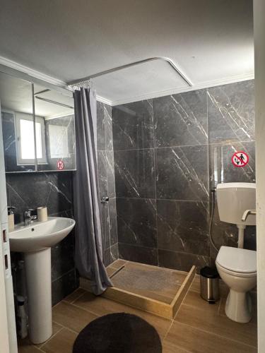 a bathroom with a shower and a toilet and a sink at Nikistratos Cozy Apartment in Néa Alikarnassós