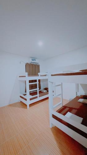 a room with two white bunk beds and a wooden floor at Family Island House in Casa Verde Mati City in Mati