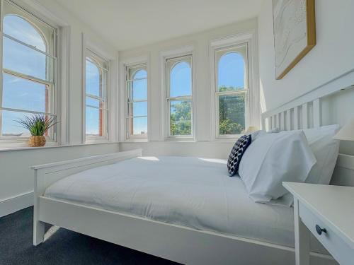 a white bedroom with windows and a large bed at Euston Road - Beach Apartment 4 in Great Yarmouth