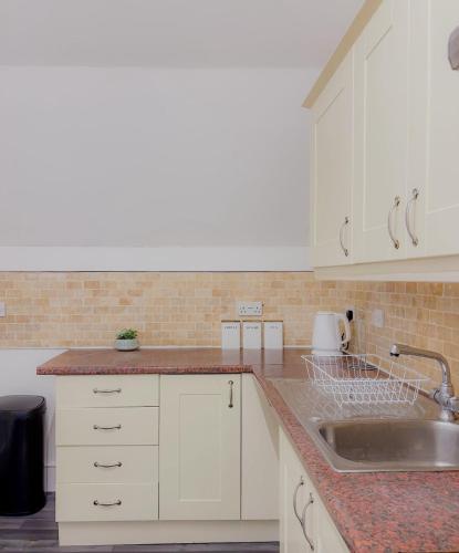 a kitchen with white cabinets and a sink at Euston Road - Beach Apartment 4 in Great Yarmouth