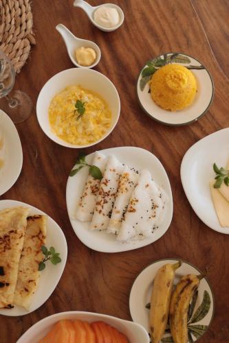 een houten tafel met borden met eten erop bij KANAHA BEACH VILLA in Icaraí