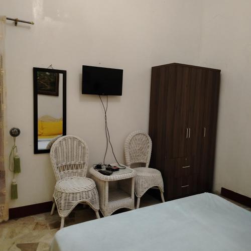 a bedroom with a bed and two chairs and a cabinet at White & Yellow Castle Hotel and Resort in Calatagan
