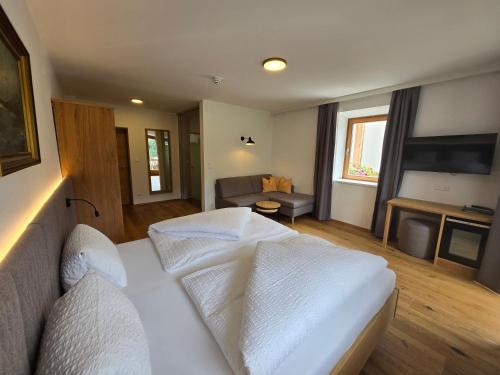 a bedroom with a white bed and a couch at Ferienhof Neusacher Moser in Weissensee