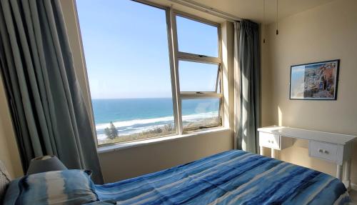 a bedroom with a view of the ocean from a window at Scottburgh Views - Smile and Wave in Scottburgh