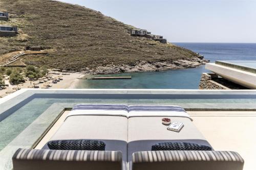 a book laying on top of a pool with a view of the ocean at One&Only Kéa Island in Pisses