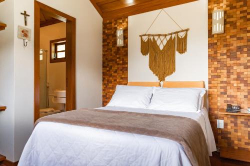 a bedroom with a bed and a brick wall at Pousada Bela Aurora in Venda Nova do Imigrante