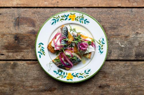 a plate of food with vegetables on a wooden table at Artist Residence Cornwall in Penzance