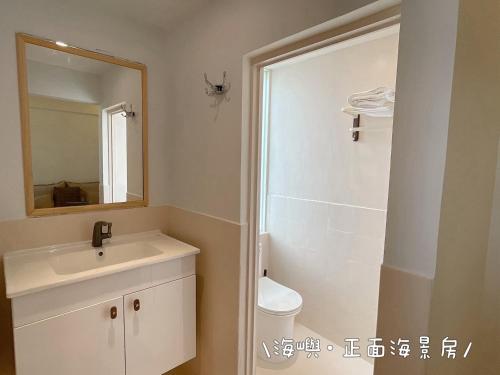 a bathroom with a sink and a mirror and a toilet at QBE 民宿 南灣館 QBE Nanwan in Nanwan