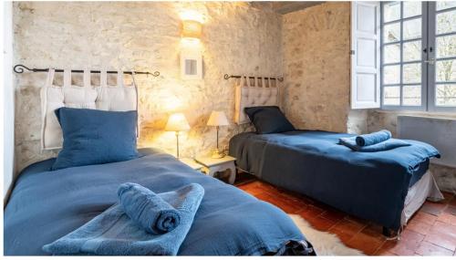a bedroom with two beds with blue sheets at Les Remparts de Sainte-Suzanne in Sainte-Suzanne