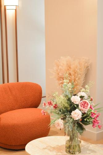 a vase filled with flowers sitting next to a chair at Dièse Hôtel Bastille in Paris
