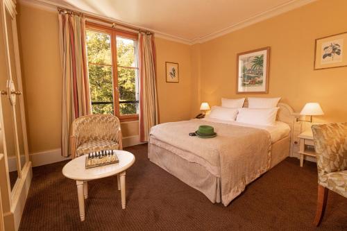 a bedroom with a bed and a chair and a window at Le Grand Hôtel - Domaine De Divonne in Divonne-les-Bains