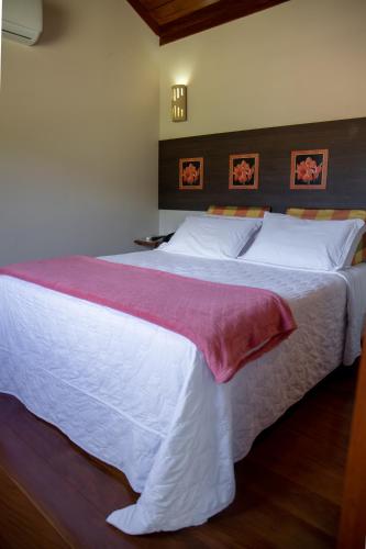 a bedroom with a large bed with white sheets at Pousada Bela Aurora in Venda Nova do Imigrante