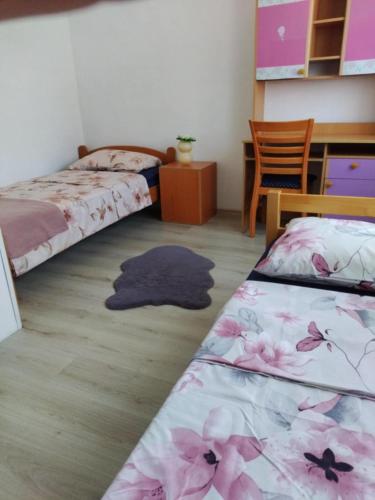 a bedroom with two beds and a table and a desk at Hiža Guesthouse in Sarajevo