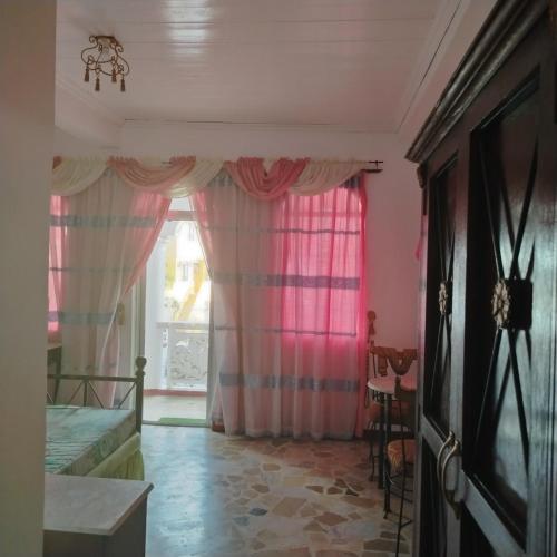 a bedroom with pink curtains and a window at White & Yellow Castle Hotel and Resort in Calatagan