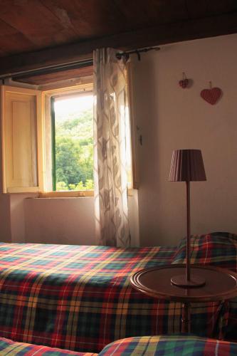 a bedroom with a bed with a table and a window at Casa l'Acerone in Pian degli Ontani