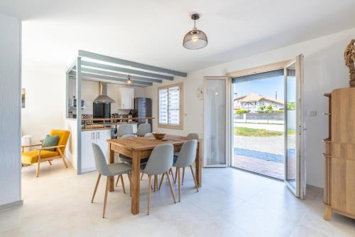 a kitchen and dining room with a wooden table and chairs at Gemma - 5 min de la Plage in Ondres